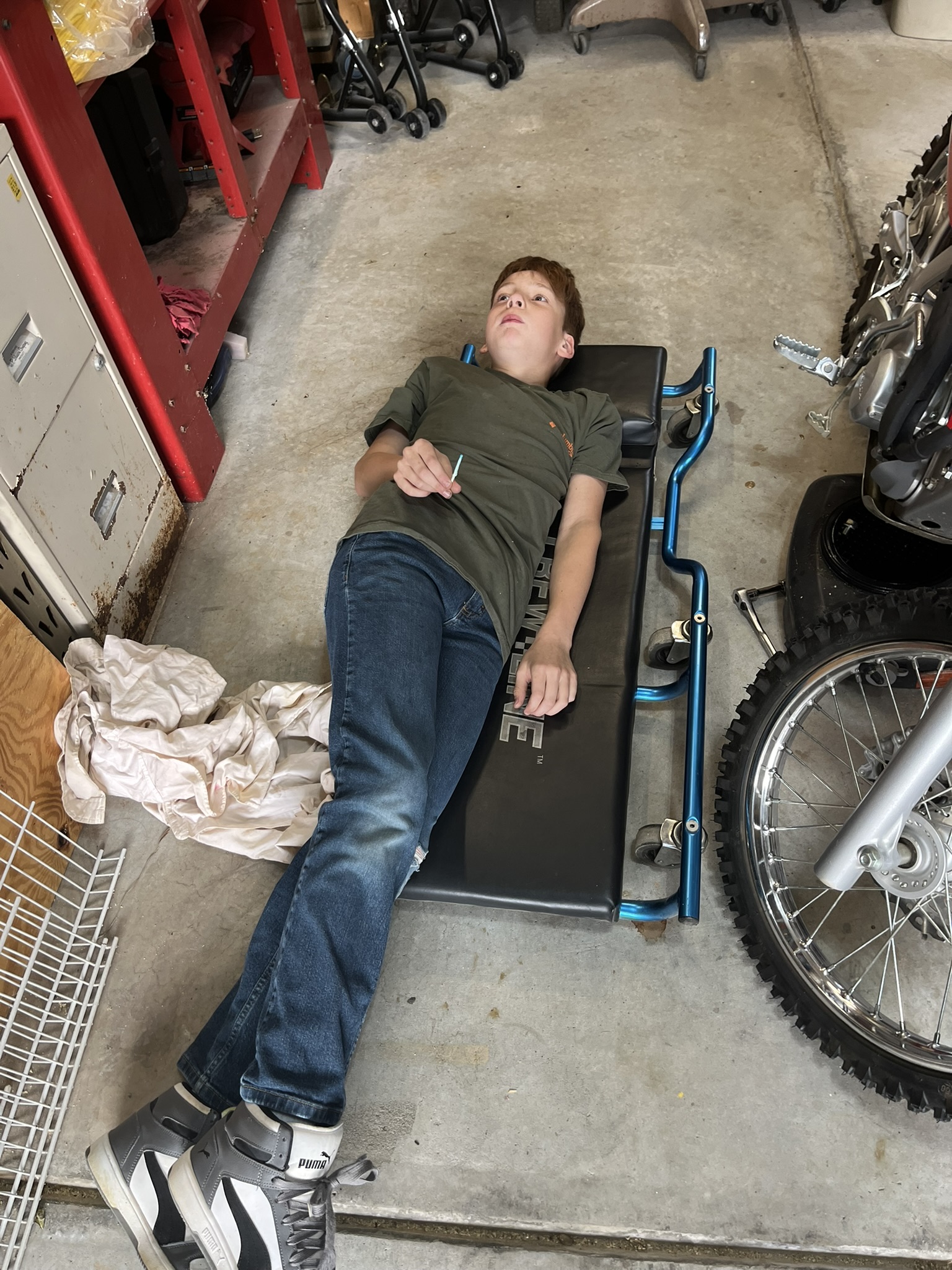 Michael on mechanic's creeper in garage